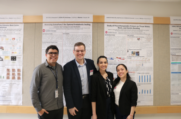 students standing in front of their posters at clinic and research day